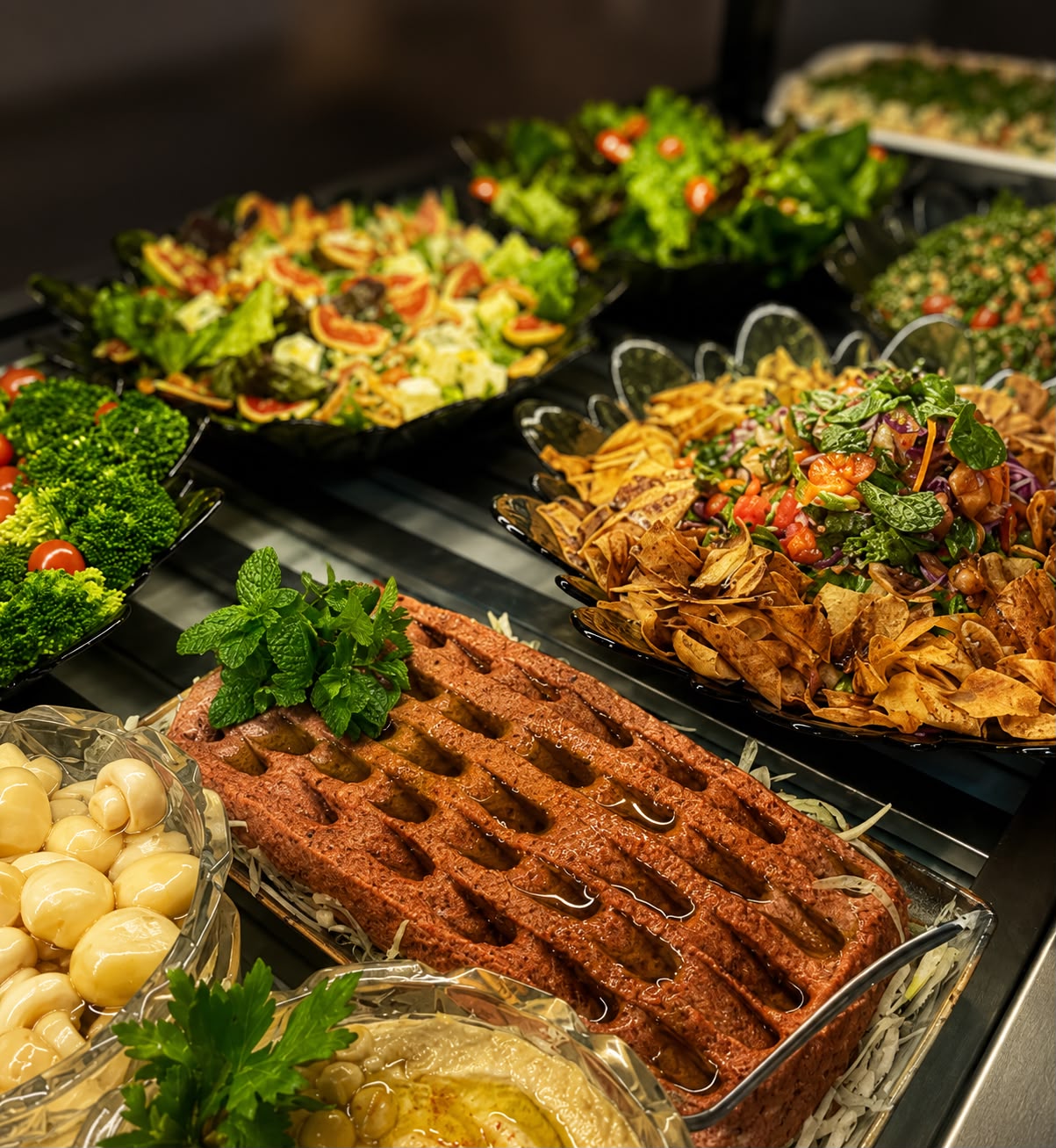 Vitrine de pratos árabes: quibe cru decorado com hortelã, homus, salada fattoush e saladas frescas